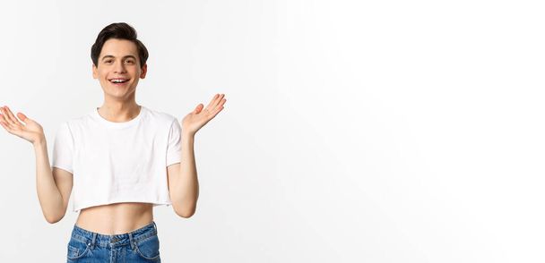 Lgbtq and pride concept. Happy and satisfied young gay man in crop top clapping hands proud, smiling at camera, standing over white background. - Fotografie, Obrázek