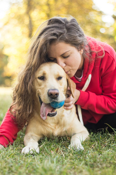 Junge lächelnde Frau mit ihrem süßen Hund im öffentlichen Park - Foto, Bild