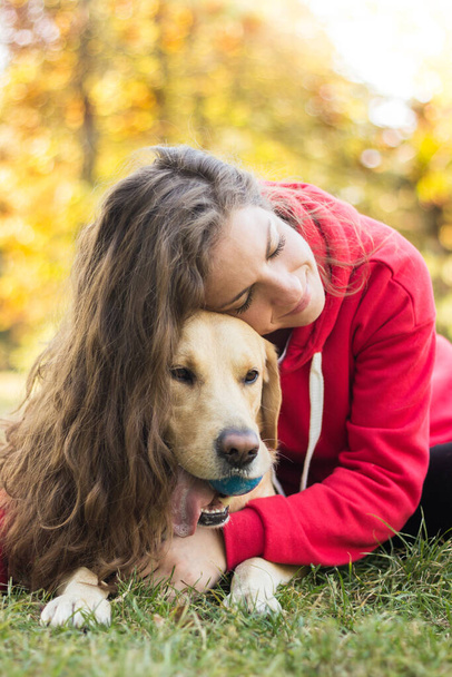Parkta sevimli köpeğiyle gülümseyen genç bir kadın. - Fotoğraf, Görsel