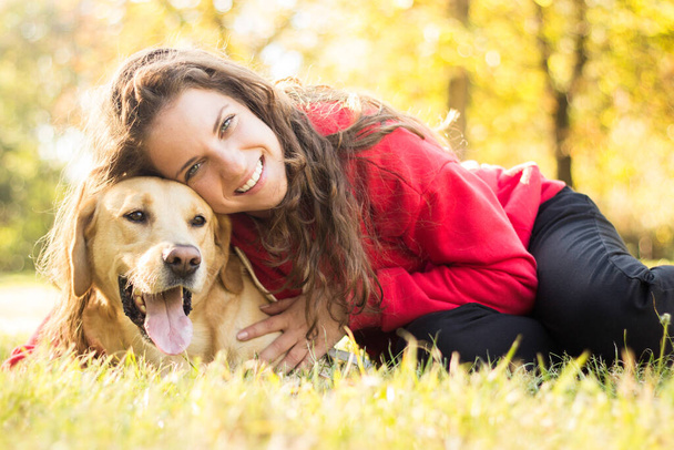 Young smiling woman with her cute dog in the public park - Foto, Imagen