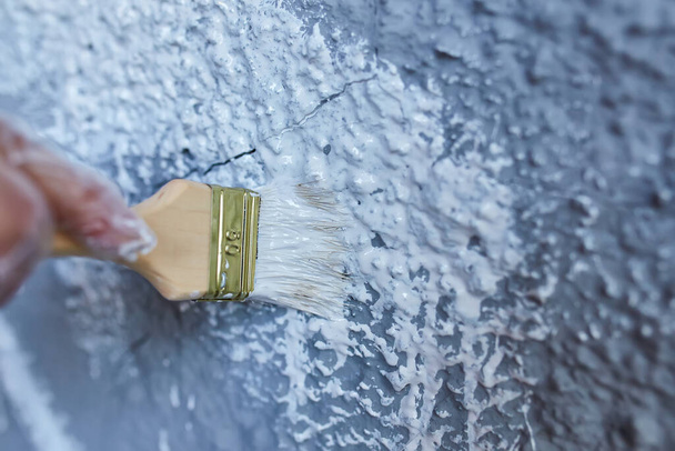 štětec v ruce maluje stěnu bílou barvu, fasádu budovy - Fotografie, Obrázek