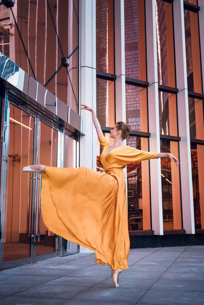Bailarina em vestido amarelo longo, vestido dançando no fundo da rua da cidade - Foto, Imagem