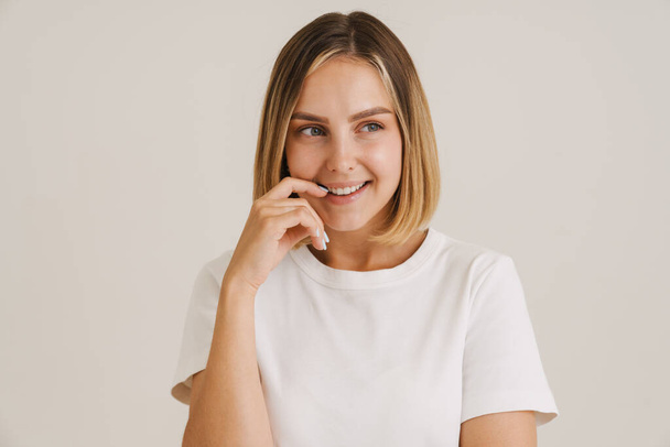 Young blonde woman in t-shirt laughing while looking aside isolated over white background - Photo, Image