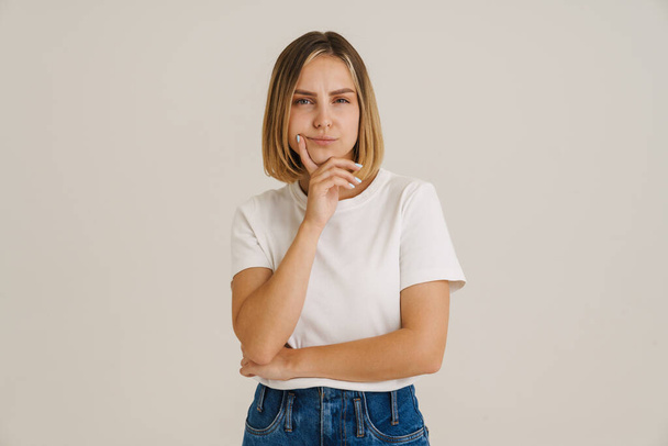Young puzzled woman wearing t-shirt looking at camera isolated over white background - Foto, afbeelding
