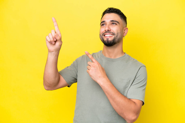 Young Arab handsome man isolated on yellow background pointing with the index finger a great idea - Foto, Imagem