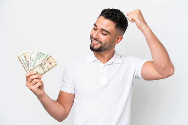 Young Arab man taking a lot of money isolated on white background celebrating a victory - Fotografie, Obrázek