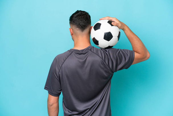 Young Arab handsome man isolated on blue background with soccer ball - Photo, Image