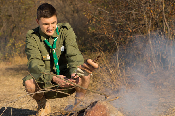 Young scout cooking his lunch over a fire - Zdjęcie, obraz