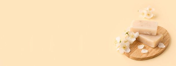 Bord met natuurlijke zeep bars en jasmijn bloemen op lichte achtergrond met ruimte voor tekst - Foto, afbeelding