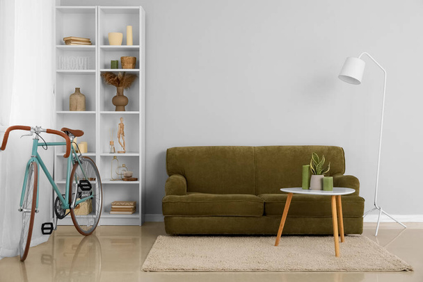 Wnętrze nowoczesnego salonu z rowerem, zieloną sofą i regałami - Zdjęcie, obraz