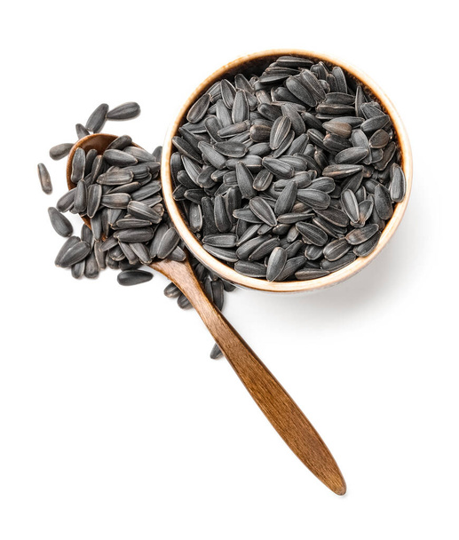 Bowl and wooden spoon with unpeeled sunflower seeds on white background - Photo, Image