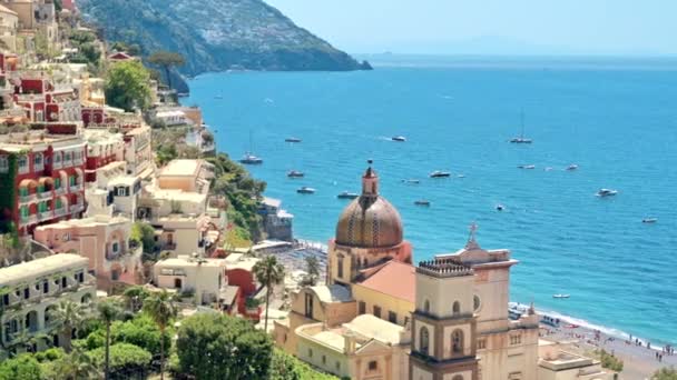Paisaje callejero de Positano, situado en la costa del mar Tirreno, Italia. Filas de edificios residenciales, iglesia, vegetación, barcos en la distancia - Imágenes, Vídeo