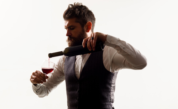 Κομψό σερβιτόρος ή οινοχόος ρίχνει κόκκινο κρασί με μπουκάλι σε ποτήρι κρασιού. Γευστική αλκοόλη - Φωτογραφία, εικόνα
