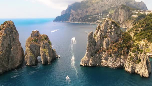 Vista aérea del dron de la costa del mar Tirreno de Capri, Italia. Acantilados rocosos, agua azul, barcos flotantes, vegetación, ciudad en la distancia - Imágenes, Vídeo