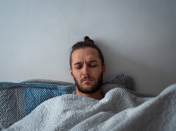 Biały człowiek w łóżku z zamkniętymi oczami cierpi z powodu bólu - Zdjęcie, obraz