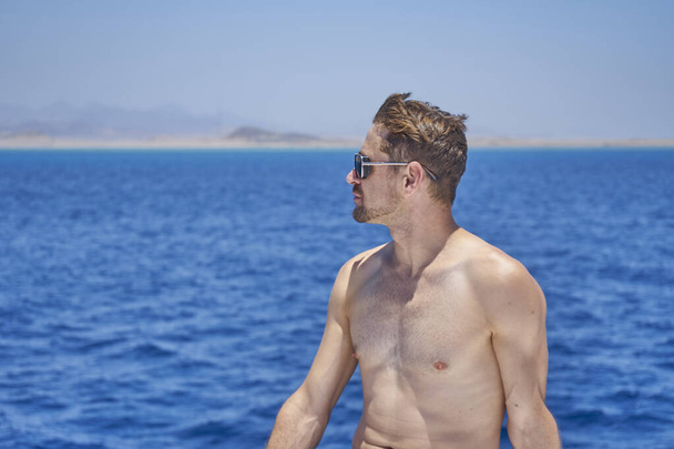 Photo of handsome happy attractive man outdoors posing on yacht in Red sea.enjoys crew duty, luxury holidays, yachting sport activities, sailing the oceans, summer vacation and recreation                                            - Foto, afbeelding