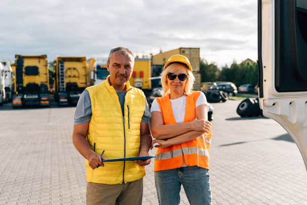 Mature woman and man at cargo warehouse, truck drivers delivery inspection . High quality photo - Fotografie, Obrázek