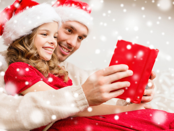 smiling father and girl in santa hats reading book - Zdjęcie, obraz