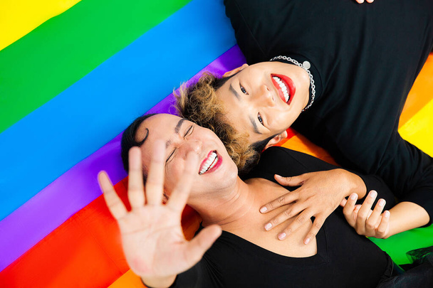Happy asian gay couple lay down on pride flag rainbow color background. lgbtq and lgbtq+ concepts - Fotoğraf, Görsel