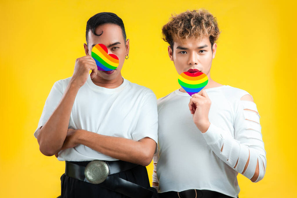 Photo de couple gay asiatique tenant la fierté drapeau arc-en-ciel papier coeur fond de couleur. concepts lgbtq et lgbtq + - Photo, image