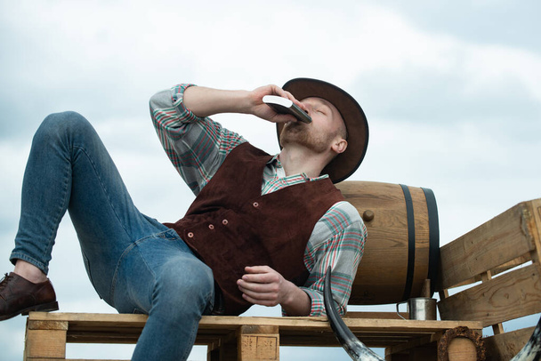 Portrait of farmer or cowboy outdoor. Guy drinking whiskey - Photo, Image