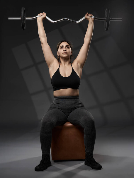 Strong size plus indian woman doing fitness workout with weights, on grey background - Φωτογραφία, εικόνα