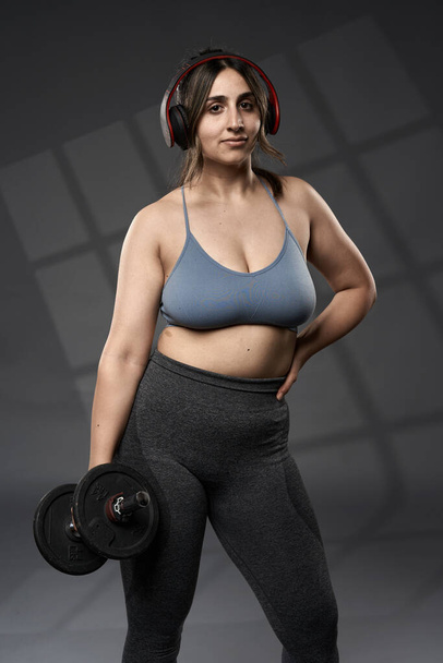 Strong size plus indian woman doing fitness workout with weights, on grey background - Foto, immagini
