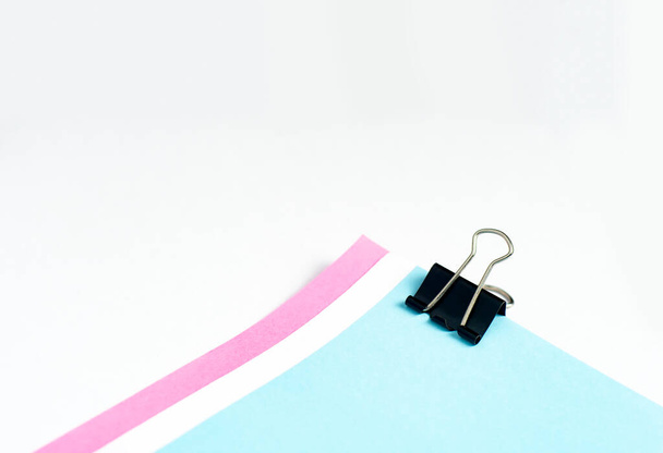 An image isolated binder clip black color stationery paper with a color paper stack for office paperclip on the white background with copy space for text. - 写真・画像