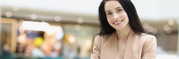 Portret pięknej młodej kobiety czekającej na randkę w kawiarni w centrum handlowym. Uśmiechnięta dama używająca smartfona do zabicia czasu. Spotkanie, czekanie, nudna koncepcja - Zdjęcie, obraz