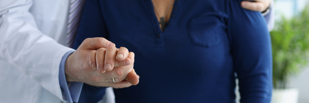 Крупним планом медичний працівник у формі допомагає літній жінці ходити тримаючись за руку. Обрізана фотографія зустрічі в клініці. Доктор, підтримка, концепція здоров'я
 - Фото, зображення