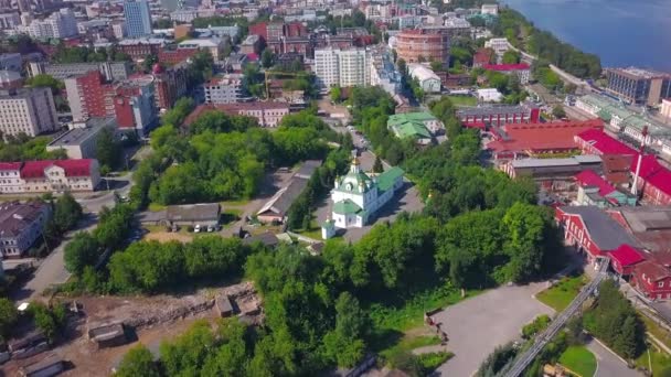 Vista aérea de un distrito de la ciudad de verano con una iglesia y casas. Clip. Hermosa ciudad verde situada junto al largo río - Metraje, vídeo