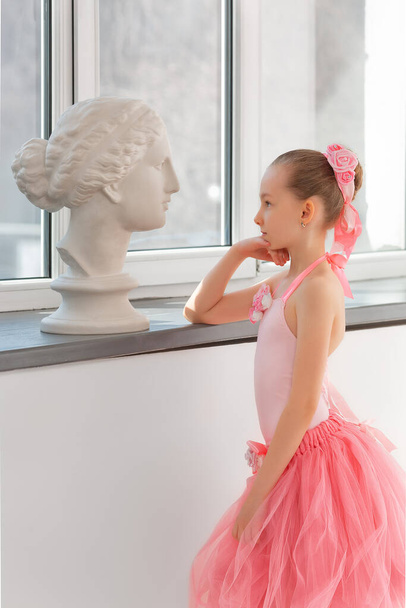 Girl ballerina in a tutu by the window with a statue of Venus - Zdjęcie, obraz