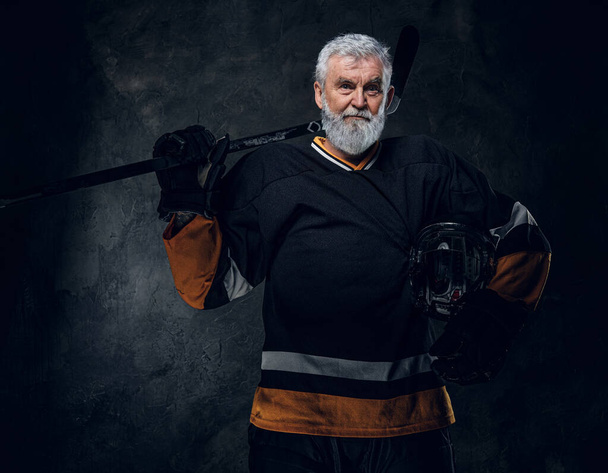 Studio shot di giocatore di hockey professionista senior con copricapo e bastone da hockey. - Foto, immagini