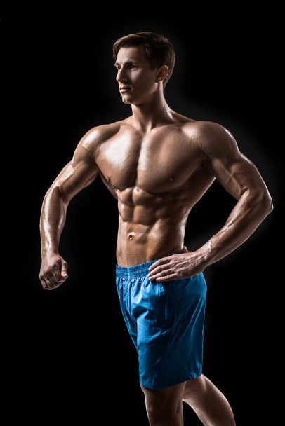 Muscular e ajuste jovem fisiculturista fitness modelo masculino posando sobre fundo preto. Estúdio tiro no fundo preto
. - Foto, Imagem