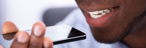 Close-up Of An African Man Using Voice Assistant On Cellphone - Fotografie, Obrázek
