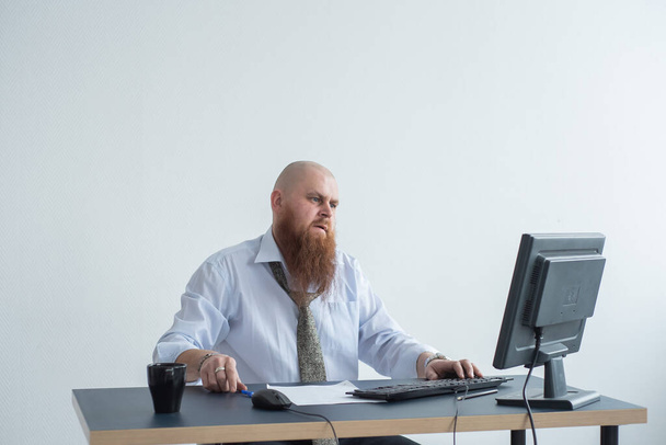 Problemen voor de kantoormedewerker. Een kale man in een wit shirt zit aan een bureau met een computer en is gestresst door een mislukking. Een zenuwinzinking - Foto, afbeelding