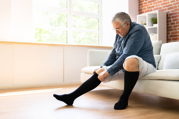 Man Putting On Medical Compression Stockings On Legs - Photo, image