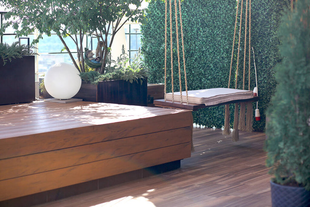 Wooden podium on the terrace with hanging swing. Photo studio on the roof. Modern interior, interior design. Landscape design concept. - Foto, imagen