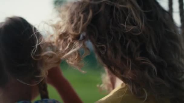 Blisko włosy kobiety na wietrze trzymając córkę na kolanie i huśtawki w letni dzień   - Materiał filmowy, wideo