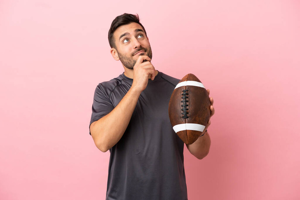 Young caucasian man playing rugby isolated on pink background and looking up - Foto, Imagem