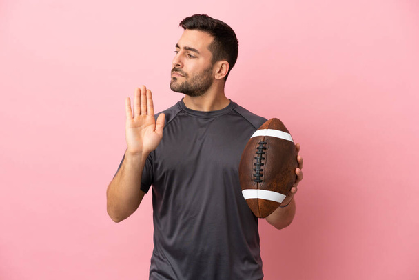 Young caucasian man playing rugby isolated on pink background making stop gesture and disappointed - Photo, Image