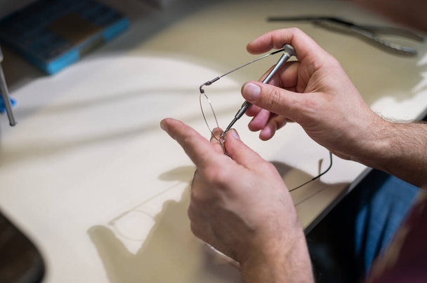 Installation of nose pads in glasses. A male technician repairs broken glasses. - Fotó, kép