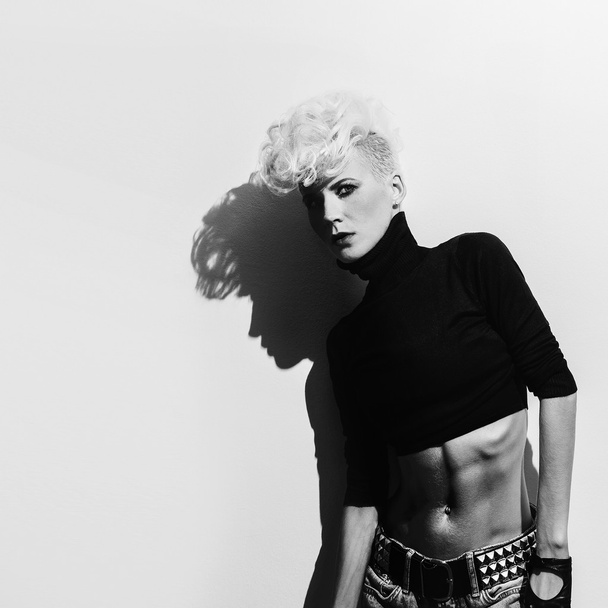 Blond model on wall background with shadow. Stylish haircut. pun - Photo, image