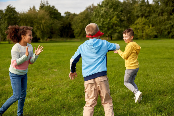 childhood, leisure and people concept - group of happy children playing tag game and running at park - Foto, afbeelding