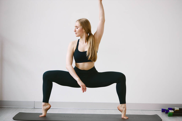 Athletic beautiful girl doing yoga and stretching in quarantine - Valokuva, kuva