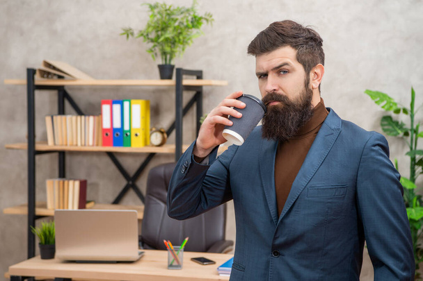 serious bearded businessman drinking takeaway coffee in the office with copy space, takeaway. - Photo, Image