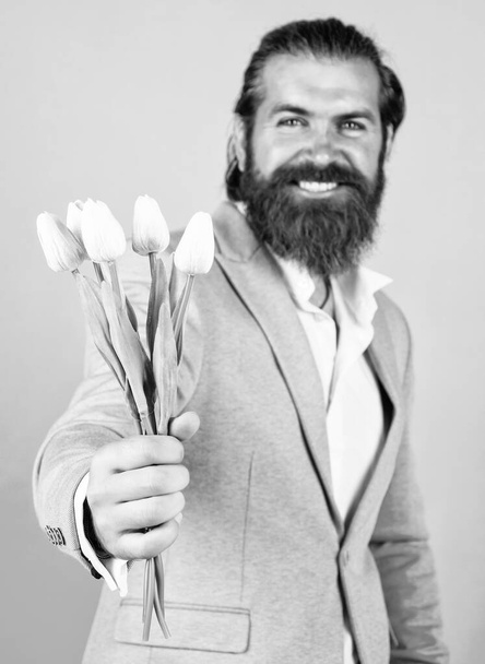 Excitement. man with beard and stylish hair. holiday and celebration. floral gift for mothers or womens day. happy man with tulip flowers. gentleman hold flower bouquet. concept of flower shop. - Фото, зображення
