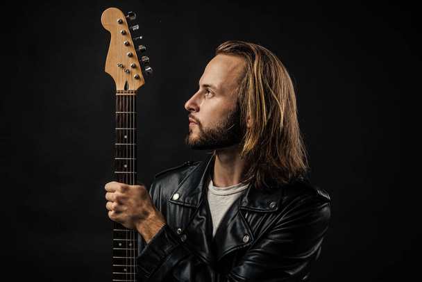 bearded rock musician with electric guitar neck in leather jacket, music. - Foto, imagen