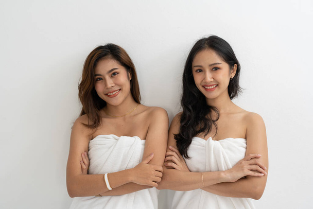 Portrait of Smiling young LGBT lesbian couple wearing a white towel standing and hugging each other affectionately together - Photo, Image