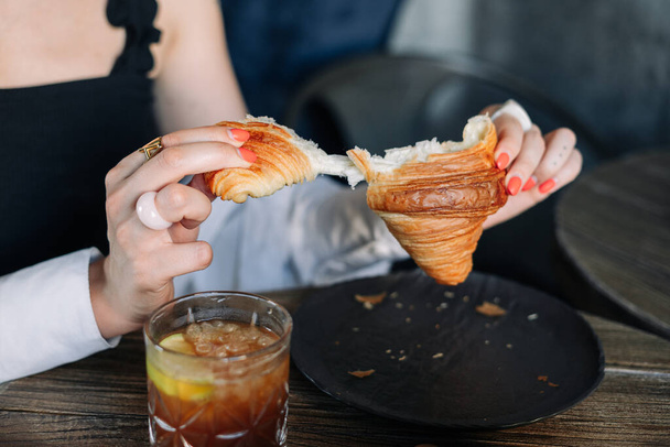 mujer joven comiendo un croissant y beber café - Foto, Imagen